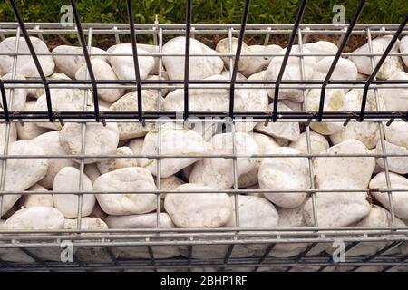 A low foundation under a steel openwork fence. Gabion. Stock Photo