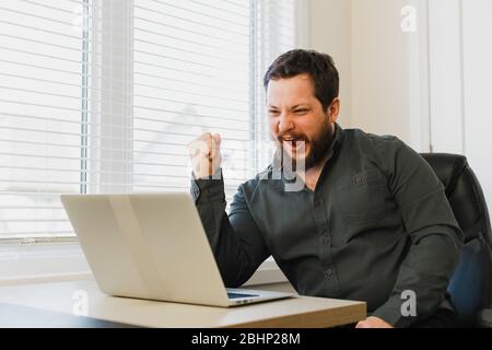 Successful enterpreneur sitting at office with laptop near window. Stock Photo