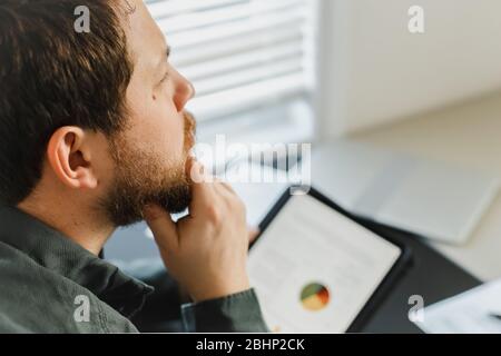 Closeup thinking financier using tablet and looking at graphs with diagrams on screen. Stock Photo