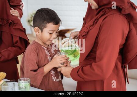 mother pour sweet drink for child to break fast with family at home Stock Photo