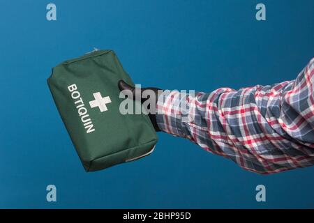 Green fabric medicine cabinet in hand with black hygienic glove. First-aid kit. Stock Photo