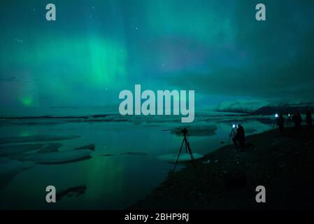 Photographers photographing the Aurora Borealis at Jökulsárlón glacier lake, Iceland Stock Photo