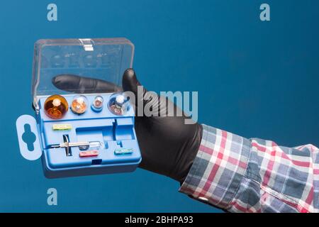 Lights and mandatory replacement material for cars in a plastic box and on hand with black glove and blue background Stock Photo