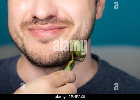 Bearded man is using jade face roller Stock Photo