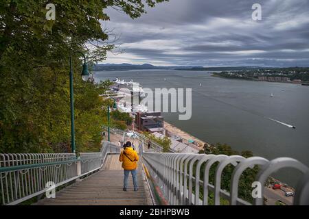 Quebec city, Canada september 23, 2018: photographer in an orange jacket at the stairs photo taken on Dufferin Terrace with the St. Lawrence river Stock Photo