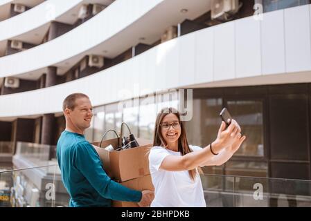 Beautiful caucasian man and woman taking selfies in front of building. Love and moving Stock Photo
