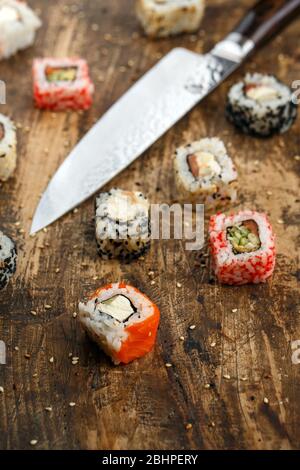 Sushi nigiri with salmon and Philadelphia sushi roll with sushi knife on wooden background. Stock Photo