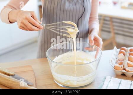 Unrecognizable woman making dough for cupcakes using whip, horizontal high angle shot Stock Photo
