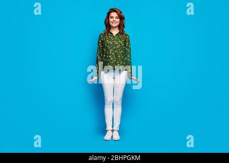 Full length photo of cute pretty cheerful lady good mood flirty shy person wear green dotted shirt white pants footwear isolated blue bright color Stock Photo