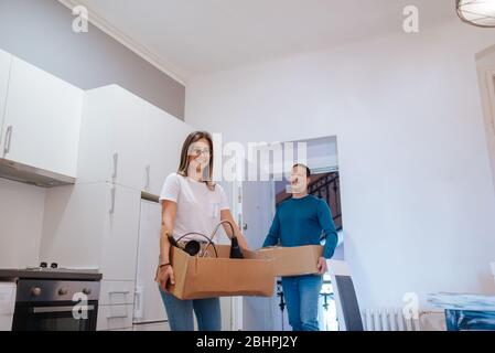 An attractive caucasian man and woman are entering a new apartment with boxes of things. A loving couple moves in