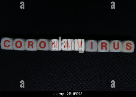 Wooden orange and white letters dice forming the writing "CORONAVIRUS" on a black background. Corona virus danger news. Stock Photo