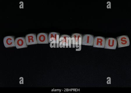 Wooden orange and white letters dice forming the writing "CORONAVIRUS" on a black background. Corona virus danger news. Stock Photo