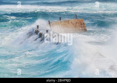 Sennen Harbour breakwater, waves crash over the sea wall during Storm Lorenzo Stock Photo
