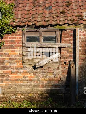Boarded up window in old abandoned brick building i. April, 2020 Stock Photo