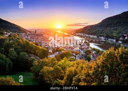 Travel shot: aerial view of Heidelberg, Germany, in beautiful sunset light, framed by colorful trees and gold and purple clear sky, with the Neckar ri Stock Photo