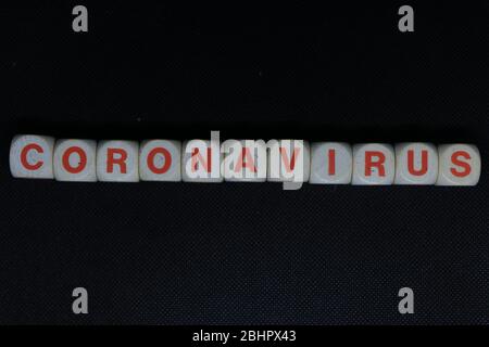 Wooden orange and white letters dice forming the writing "CORONAVIRUS" on a black background. Corona virus danger news. Stock Photo