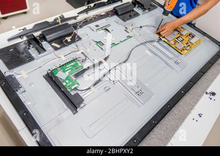 A TV mechanic is trying to replace the TV motherboard of LCD TV Sharp 65 inch at Huahin, Thailand April 25, 2018 Stock Photo