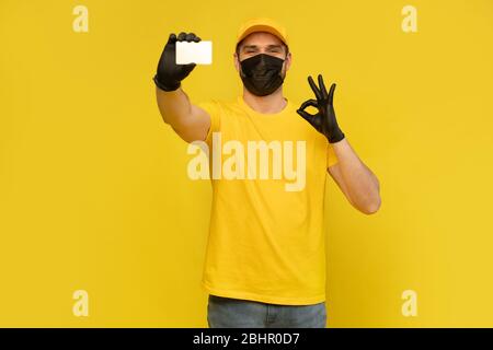 Handsome courier with business card on yellow background, closeup. Stock Photo
