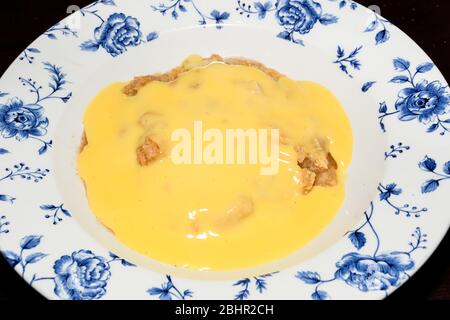 Traditional English apple pie with vanilla pudding on top, served in an old style plate Stock Photo