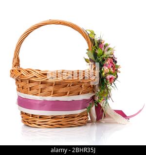 Brown wicker basket. Decor with pink flowers, greenery and ribbons. Made for Easter. Side view. Stock Photo