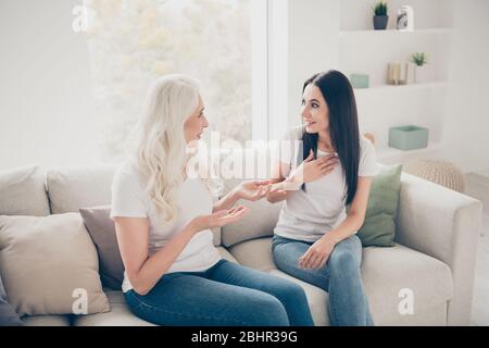 Portrait of two nice attractive cheerful friendly women talking discussing news sharing secrets spending time day together in white light interior Stock Photo