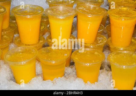 Closeup of many red yellow juice drink cocktail plastic cups beverages and cover in shop store counter in summer Stock Photo