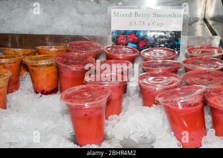 Closeup of many red yellow juice drink cocktail plastic cups beverages and cover in shop store counter in summer Stock Photo