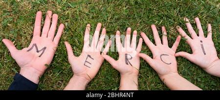Word merci written on child hands Stock Photo
