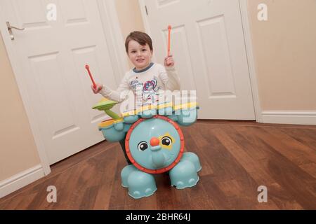 Two year old boy playing the drums at home Stock Photo