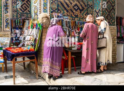 Samarqand, Uzbekistan - June 9, 2019: Square with three woman at souvenir shop near the Ulugbek Madrasasi in the centre of Samarqand in Uzbekistan. Stock Photo