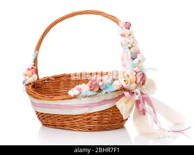 Brown baby wicker basket for Easter celebration. Bright delicate pink floral decor with ceramic decorative bunny. Stock Photo