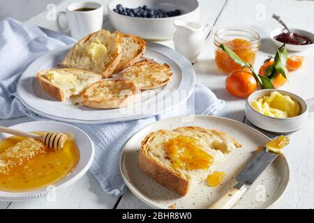 Plates of toast with butter and marmalade, dishes of honey, butter and jams. Stock Photo