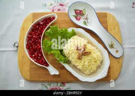 Traditional Russian salad Mimoza. Isolated on wooden background. Top view. CHICKEN SALAD with walnuts and mushrooms . Granulated pomegranate Stock Photo