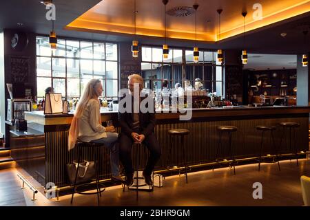A couple sitting on bar stools next to a bar. Stock Photo