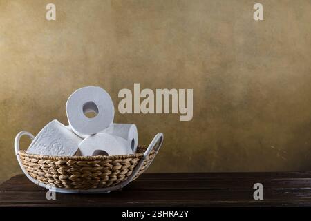 Rolls of toilet paper in the basket on the wooden background Stock Photo