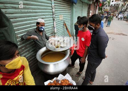 April 27, 2020: During the coronavirus (Covid-19) pandemic, and on the 4th day of Ramadan, a vendor are selling traditional food known as Halim/Iftar to the two young boys, who are waiting with wearing face masks without maintaining the social distance. They will eat it at evening for breaking the Roja in Dhaka, Bangladesh. Credit: Shafayet Hossain Apollo/ZUMA Wire/Alamy Live News Stock Photo