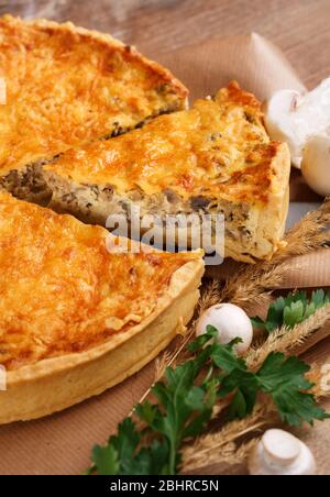 Homemade tart with puff pastry with mushrooms, cheese, onion, parsley and dill on rustic wooden table. Top view. Stock Photo