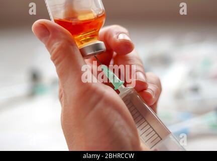 Womans hand nurse health worker holds syringe and dials medicine from bottle on white background Stock Photo