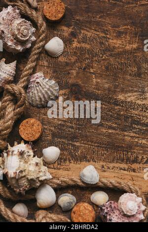 Nautical knots with rope and seashell on old burnt wooden board with place for text. Stock Photo