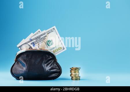 Black wallet with coins and dollars on a blue background. Budget for investment in the future. Free space, isolate Stock Photo