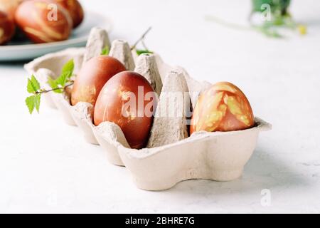 Naturally dyed with onion shells and springtime  plants Easter eggs in cardboard box, springtime  plants, zero waste concept, sustainable living Stock Photo