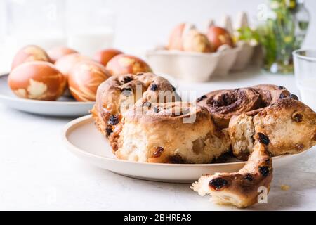 Easter brunch table. Cinnamon buns, naturally dyed with onion shells and springtime  plants Easter eggs in cardboard box, springtime  plants, zero was Stock Photo