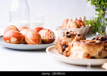 Easter brunch table. Cinnamon buns, naturally dyed with onion shells and springtime  plants Easter eggs in cardboard box, springtime  plants, zero was Stock Photo