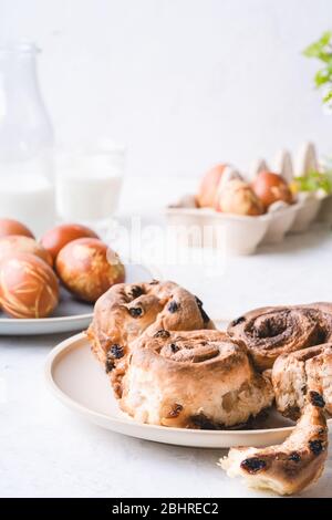 Easter brunch table. Cinnamon buns, naturally dyed with onion shells and springtime  plants Easter eggs in cardboard box, springtime  plants, zero was Stock Photo