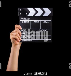 Human hand holding film clapper board isolated on black background Stock Photo