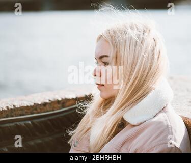 Portrait of a young girl, blonde with bleached hair, Caucasian. Scandinavian style. Close - up of a teenage woman looking past a camera in the city Stock Photo