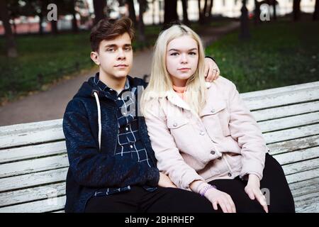 teenagers in love sit on a Park bench in autumn and stare straight ahead Stock Photo