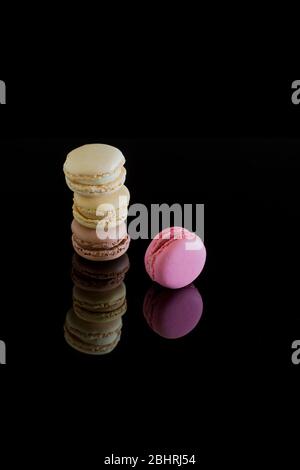 Colorful macarons with reflection isolated on a black background. Sweet French cakes. Stock Photo