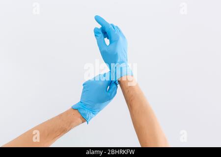 close up of Doctors hands putting on nitrile gloves isolated over white Stock Photo