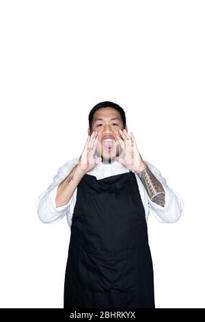 Bearded asian men waiter, chef dressed in black apron is shouting with two hands in white background.The concept of protest, attention, request. Place Stock Photo